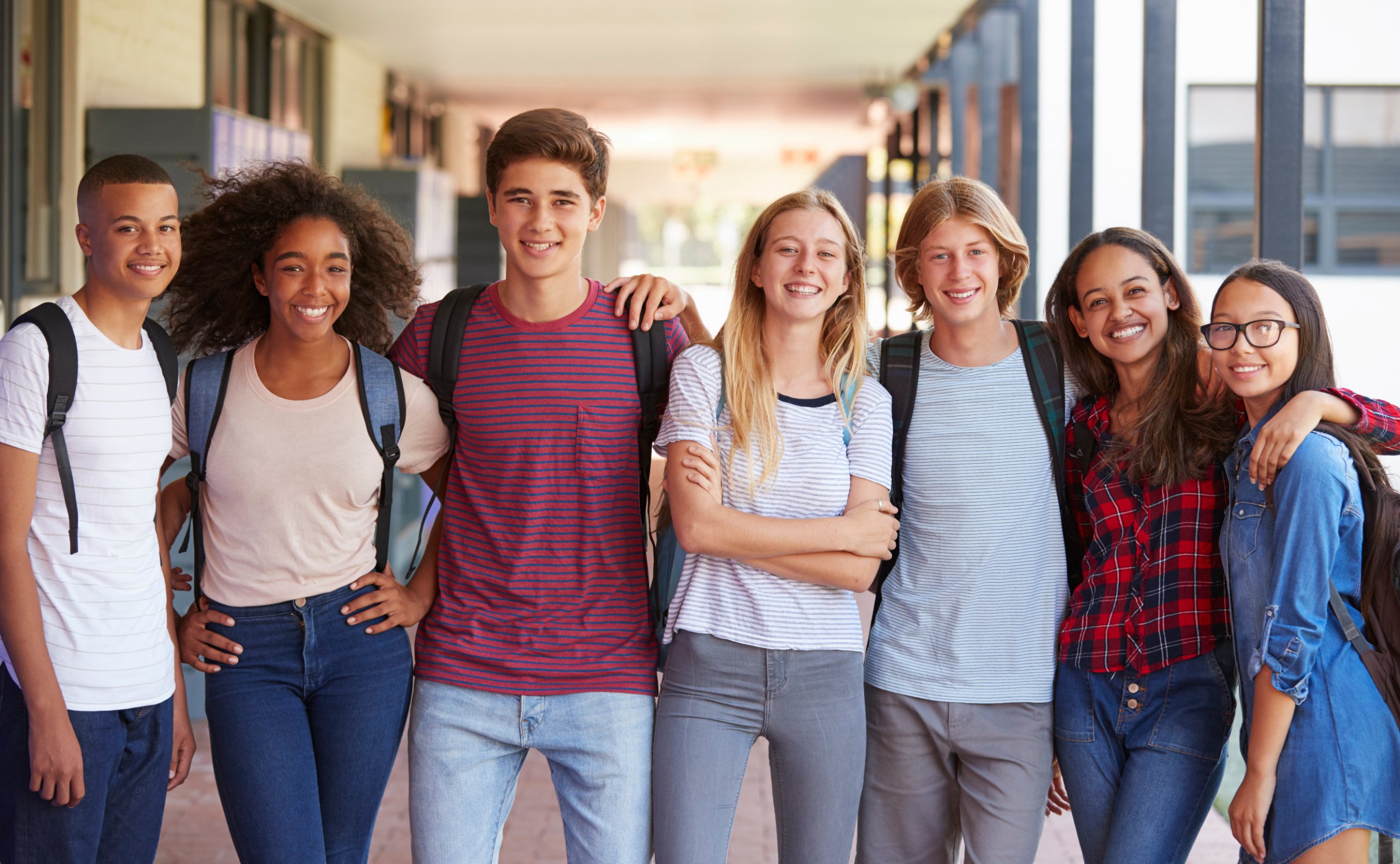A group of smiling high school students in a hallway